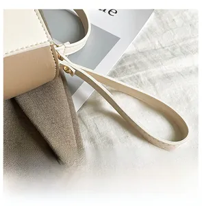 Detail view of the soft beige and brown leather handle with golden metal rivets on the bag
