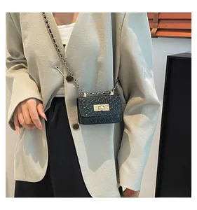 Model wearing black woven crossbody bag with gold lock and chain strap detail