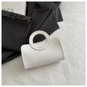 Close-up of white crocodile pattern mini bag featuring a circular hard top handle