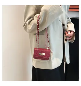 Detail of burgundy woven chain bag with gold metal lock worn on a beige blazer