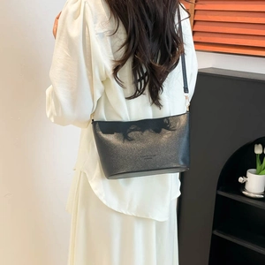 Minimalist black pebbled leather bucket bag shown as a crossbody on a female model