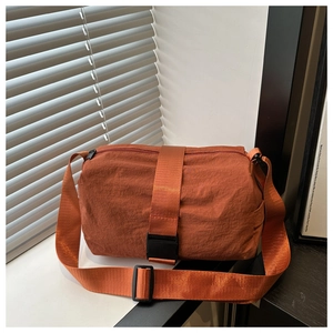 Detailed close-up of caramel nylon crossbody bag with vertical buckle and wide strap