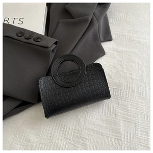 Detail of black crocodile texture mini bag with unique circular cut-out handle
