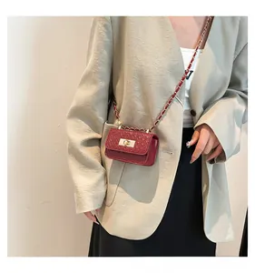 Close-up of wine red woven texture crossbody bag with gold clasp and chain strap