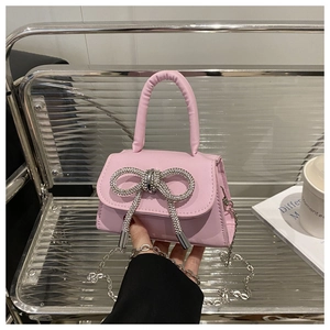 Détail du mini sac rose clair avec nœud en strass et détails de la bandoulière chaîne