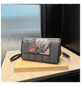 Détail du sac bandoulière à imprimé journal avec art de paysage rétro posé sur livre