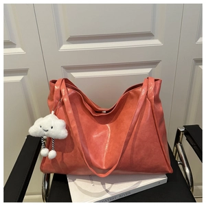 Close-up of coral orange tote bag with soft matte texture and white cloud plush charm