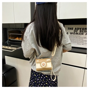 Detail of camera-shaped crossbody bag with khaki color-blocking and adjustable strap