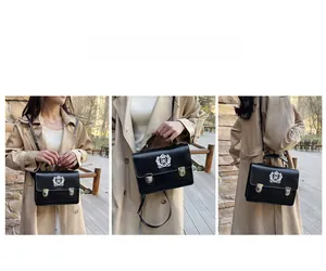 Détail du sac messager noir vintage avec broderie blason blanc et boucles métalliques