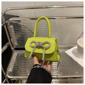 Détail du sac à main vert fluo en cuir avec nœud en strass brillant et bandoulière chaîne