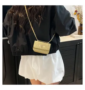 Close-up of golden crossbody chain bag with textured finish and metal buckle