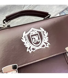 Detailed view of deep brown vintage messenger bag with white embroidered shield crest