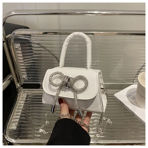 Détail du mini sac blanc en cuir avec nœud en strass et fine bandoulière en chaîne