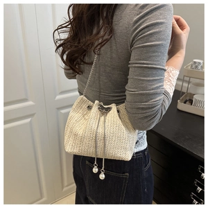 Detail of woven straw bucket bag with silver butterfly clasp and pearl drawstring