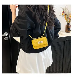 Detail view of yellow faux crocodile leather handbag with elegant gold chain strap