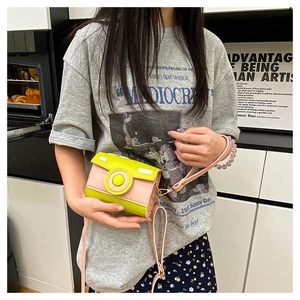 Detail of creative camera-shaped crossbody bag in neon green and pink leather material