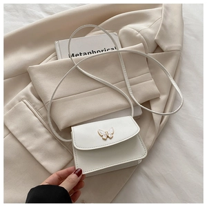 Detailed shot of a white mini square bag with an enamel butterfly and smooth leather