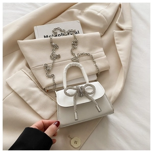 Détail du mini sac à main blanc avec nœud en strass et bandoulière en chaîne argent