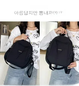 Detail view of the multi-zipper compartments on a black nylon backpack for travel