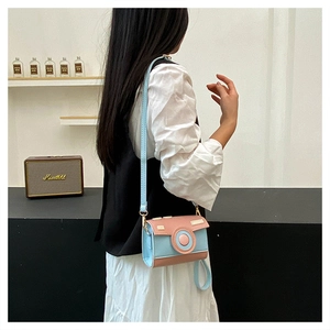 Detail view of pink and blue camera shaped crossbody bag with gold buckle on a model