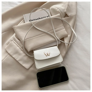 Mini white crossbody bag with gold butterfly accent shown next to a smartphone for size