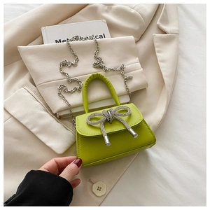 Détail du mini sac en cuir vert fluo avec un nœud en strass étincelant et bandoulière chaîne