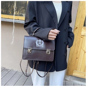 Gros plan d'un sac messager vintage marron avec broderie blason et boucles métalliques