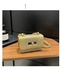 Detailed view of woven golden chain crossbody bag with metallic clasp on wooden surface