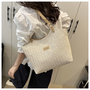 Detailed view of beige woven tote bag with khaki leather handles and fashion logo
