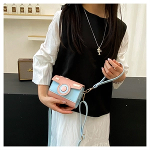 Detail of a retro camera shaped crossbody bag with pink and blue color-block design