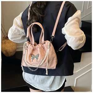 Pink drawstring bucket backpack featuring silver butterfly charm and pearl chain details
