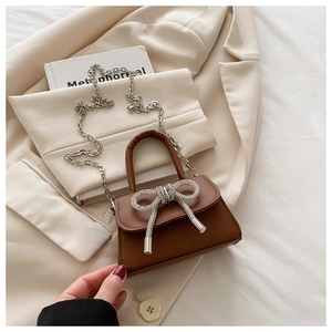Détail du mini sac en cuir marron avec boucle en strass et bandoulière en chaîne