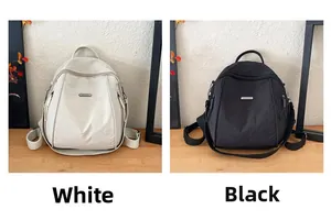 Detail view of black and white nylon backpacks with dual zippers and metal logo plaques