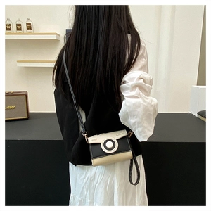 Detail of camera-shaped crossbody bag in black and white PU leather on a model
