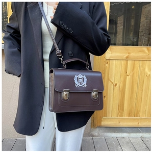 Détail du sac messager en cuir marron foncé avec broderie R et boucles argentées
