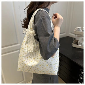 Detail of floral canvas tote bag featuring white lace bow and yellow flower pattern
