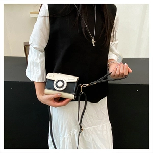 Detail of creative camera shaped crossbody bag with black and white leather contrast