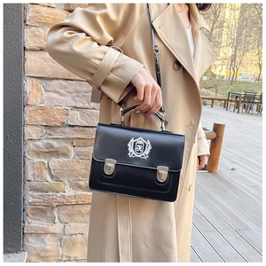 Détail du sac besace noir avec broderie blason argentée et fermeture à boucle en métal