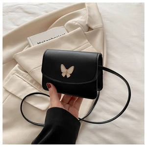 Close-up of black crossbody bag featuring a golden butterfly buckle on matte finish