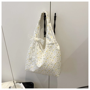 Detail of floral canvas tote bag featuring white lace bow and yellow flower pattern