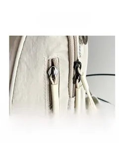Detail of a beige nylon travel backpack showing a double zipper closure and neat stitching