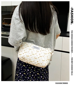 Détail du sac à bandoulière matelassé blanc avec broderie nœud doré et chaîne