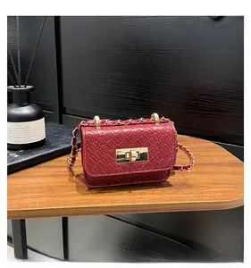 Detail of burgundy woven leather shoulder bag featuring gold twist-lock and chain strap