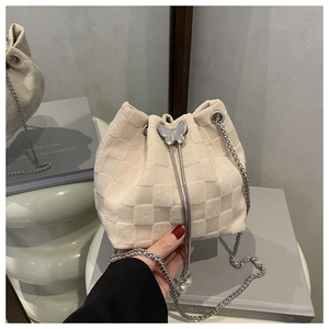 Detail of cream woven bucket bag with silver butterfly charm and pearl drawstring accents