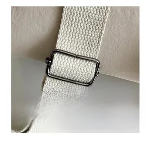 Detail view of the durable woven shoulder strap and metal adjustment ring on the nylon backpack