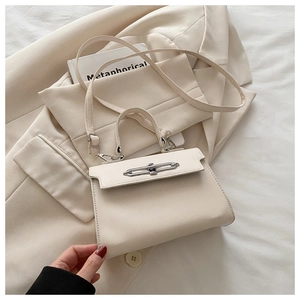 Detail of cream white leather handbag with metal buckle closure and top handle