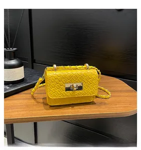 Close-up of bright yellow woven small square bag with golden twist lock and chain strap