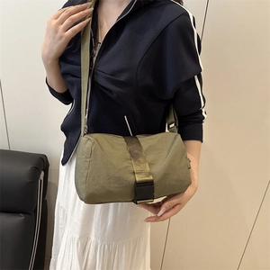 Army green nylon cylinder crossbody bag with buckle detail shown on a model