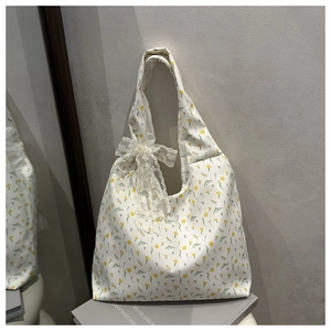 Close-up of floral canvas tote bag with white lace bow detail on a minimal background