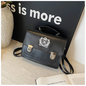 Détail du sac à dos vintage en cuir noir avec écusson brodé de style académique